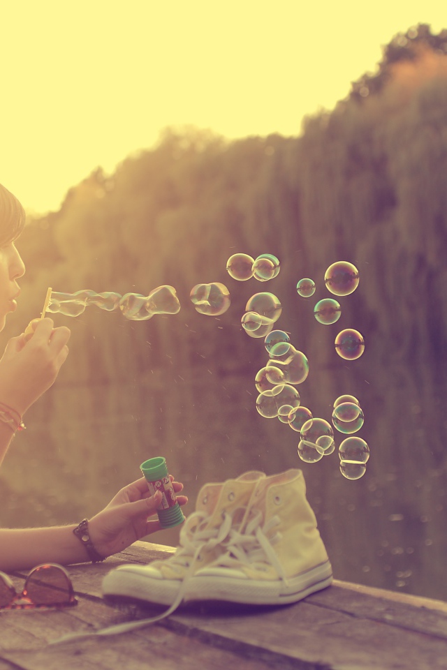 Девушка лежит на пирсе и играет с мыльными пузырями