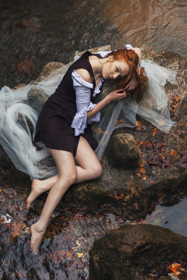 Девушка лежит на камне среди воды