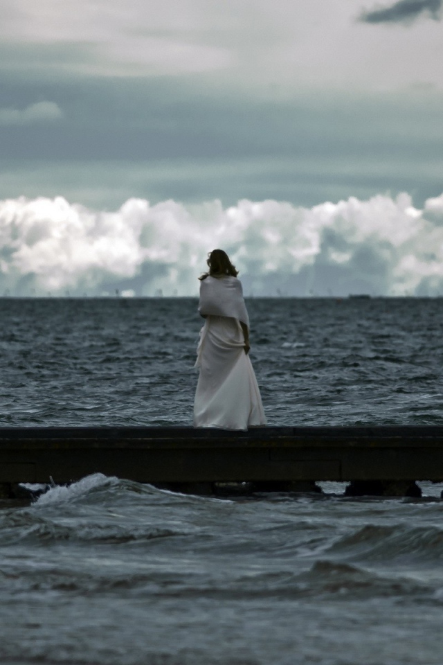 Девушка смотрит на свинцовые воды моря