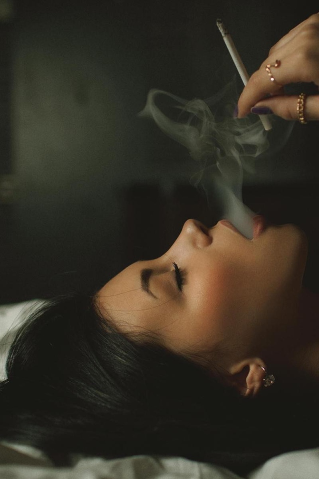 Девушка курит лежа в постели