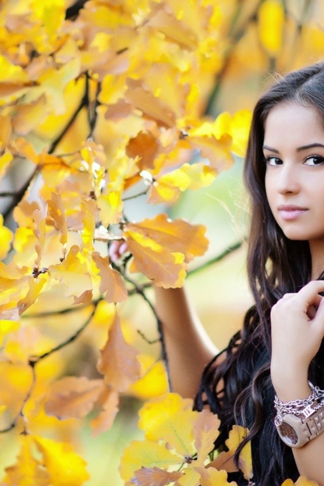 Молодая брюнетка у осеннего дерева