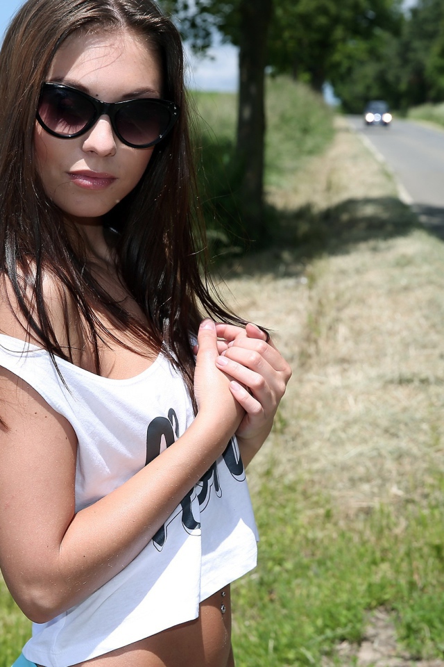 Молодая девушка в майке стоит у дороги