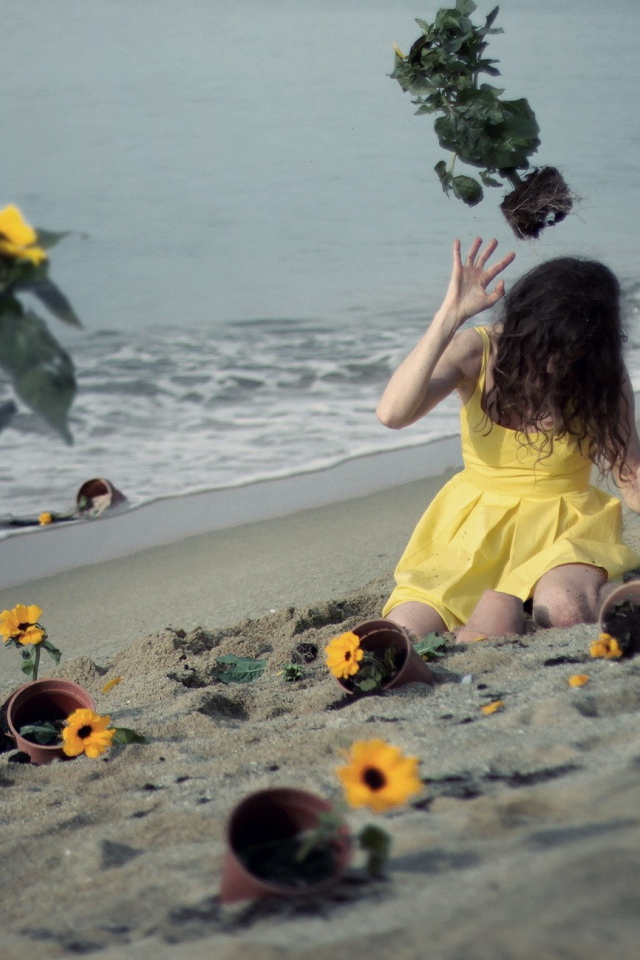 Модель в желтом платье среди цветов на пляже