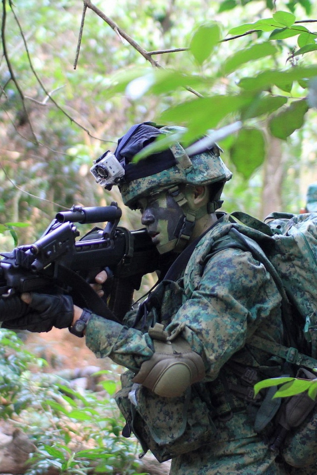 Soldiers in camouflage walking through forest