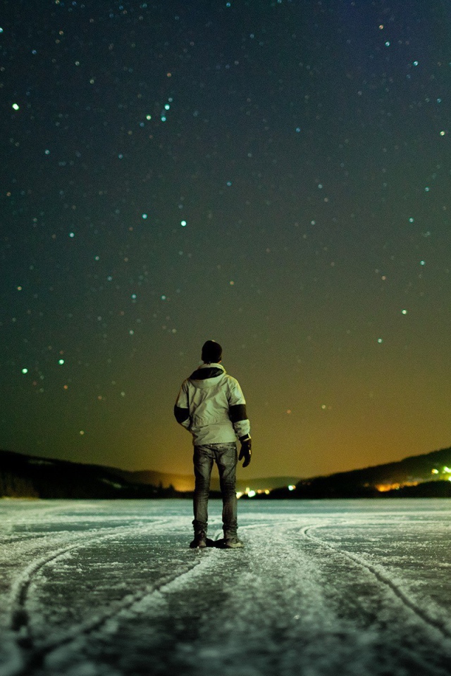 Мужчина на льду смотрит на звезды