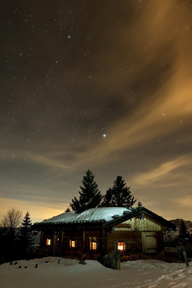 Северное сияние в небе над деревянной избушкой