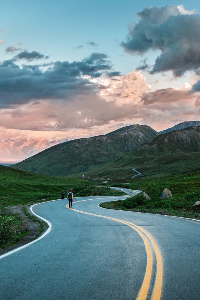 Одинокий путник на шоссе среди гор