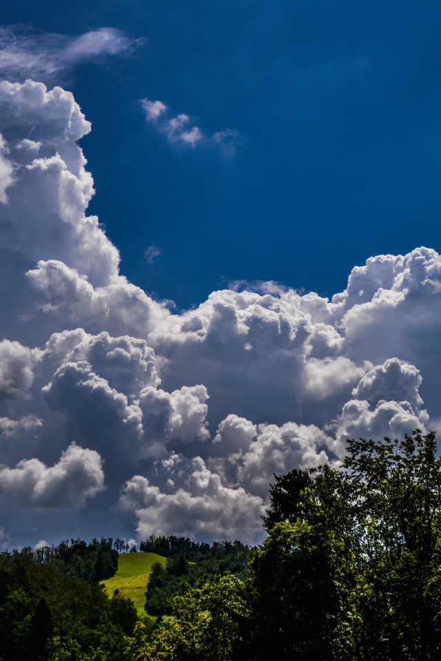 Кучевые облака над зелеными холмами