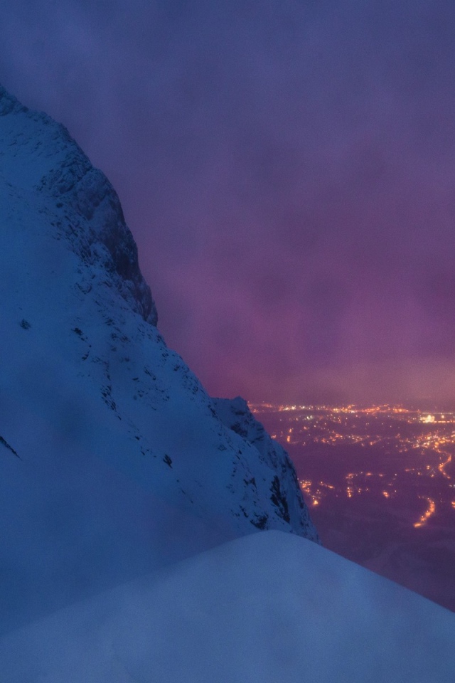 Заснеженная скала на фоне ночного города