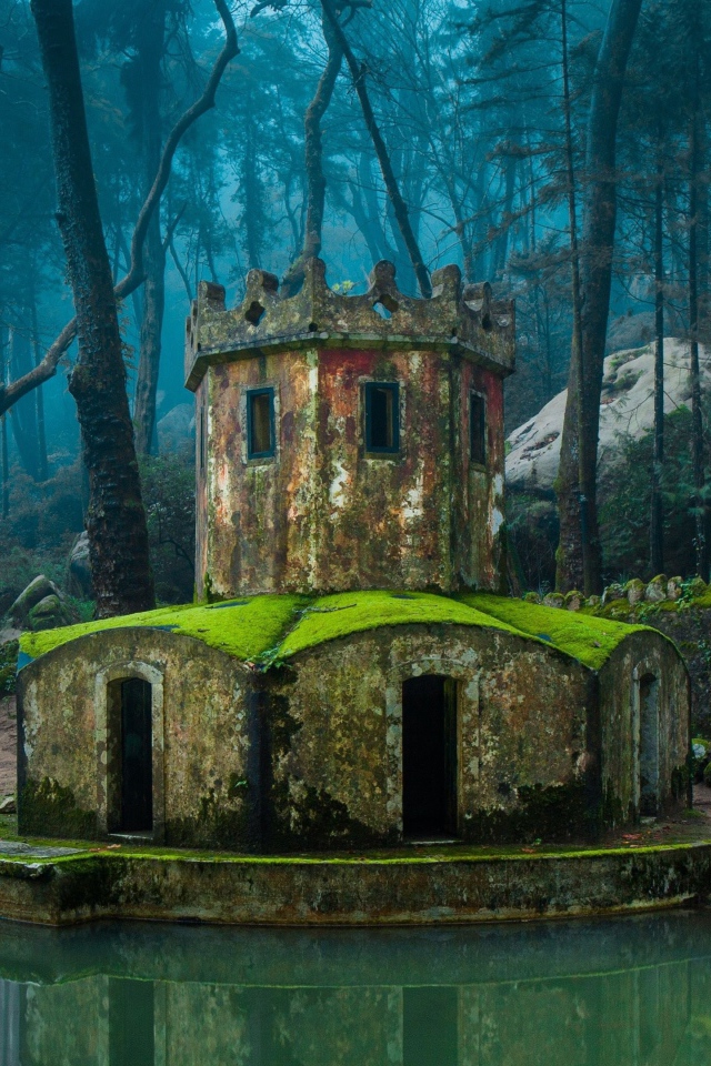 Покрытая мхом каменная беседка у воды