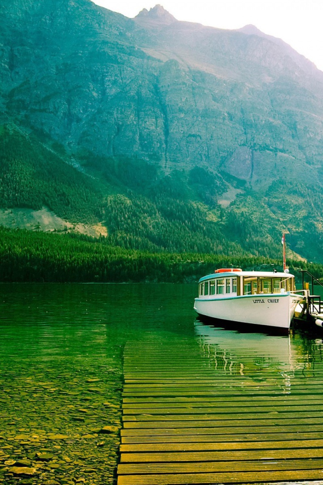 Лодка у причала на зеленой воде горного озера