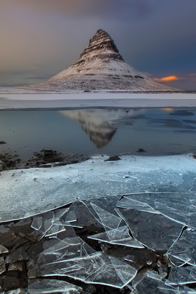 Тонкий лед озера на фоне горы