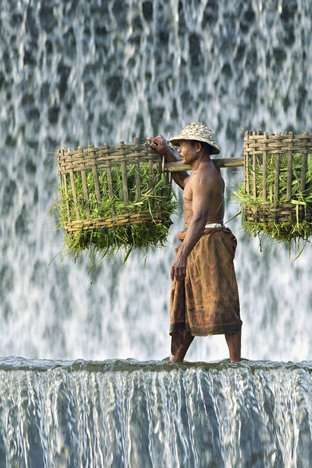 Крестьянин с корзинами идет по водопаду