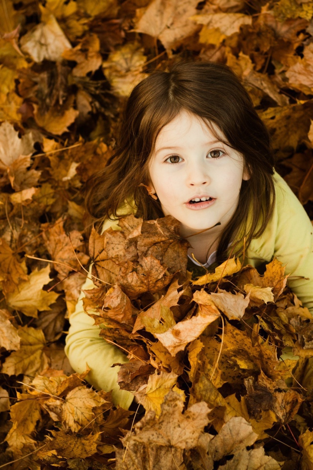 Девочка зарылась в опавшие листья
