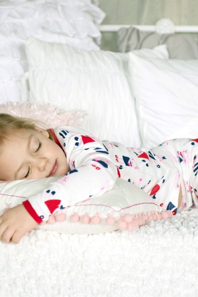 Девочка в пижаме спит на кровати