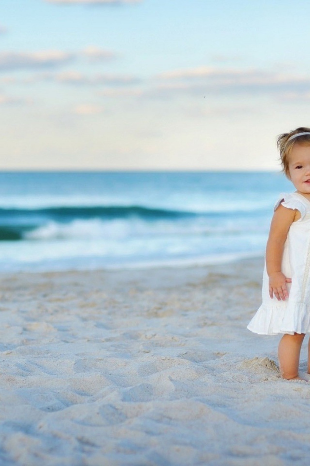 Девочка в белом платье на песке пляжа