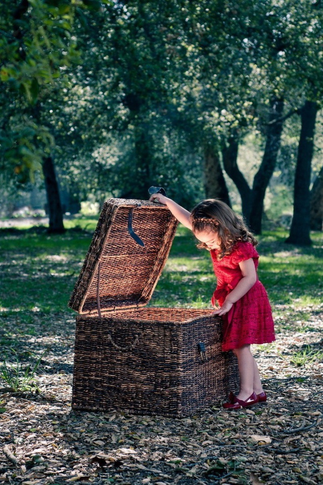 Девочка заглядывает в плетеную корзину