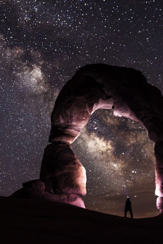 Природная каменная арка на фоне звезд