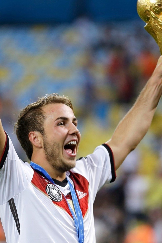 Немецкий футболист Марио Гётце держит в руке кубок