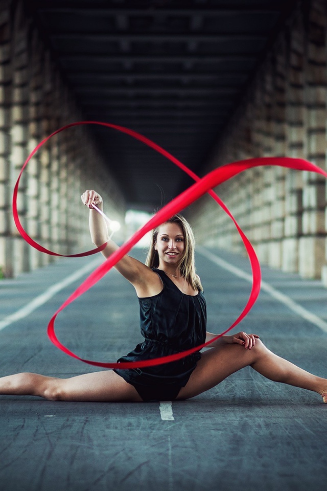 Гимнастка упражняется с красной лентой