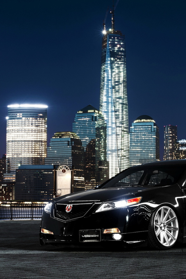 Black car Acura TL on a background of night skyscrapers