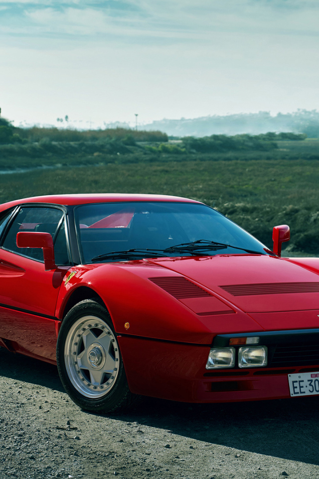 Красный быстрый автомобиль Ferrari 288 GTO у реки
