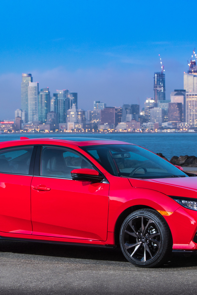 Красный автомобиль Honda Civic Touring Hatchback, 2017 на фоне города 