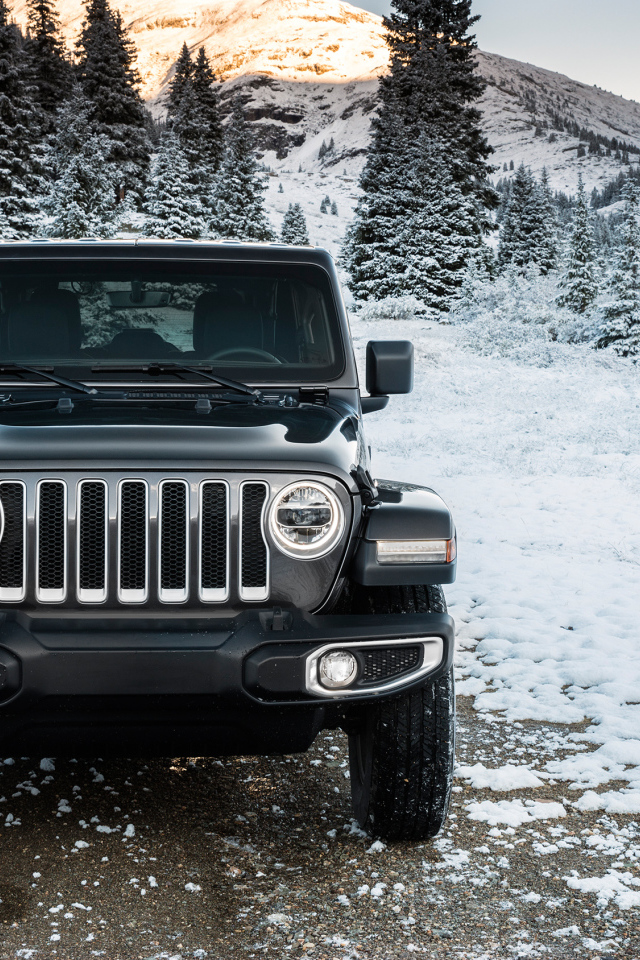 Внедорожник Jeep Wrangler Unlimited Sahara, 2018 на заснеженной дороге на фоне гор