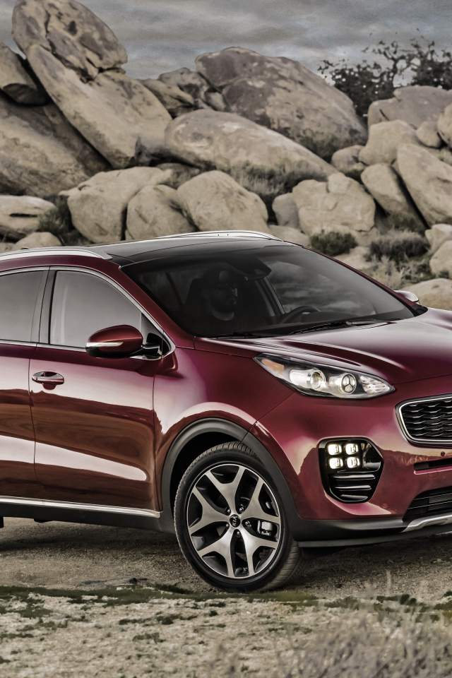 Стильный бордовый внедорожник Kia Sportage на фоне больших камней