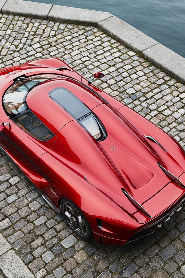 Красный спортивный автомобиль Koenigsegg Regera у воды, вид сверху