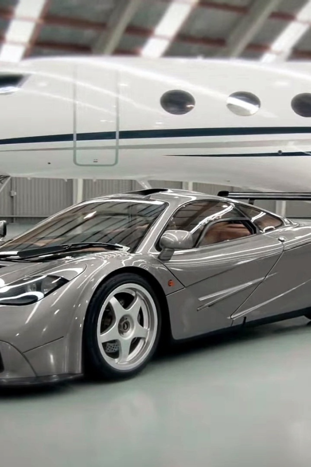 Спортивный автомобиль McLaren F1 на фоне самолета