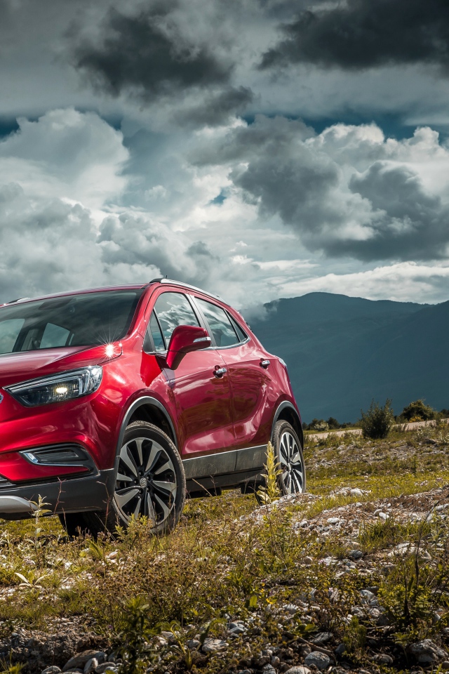 Красный автомобиль Opel Mokka на фоне облачного неба 