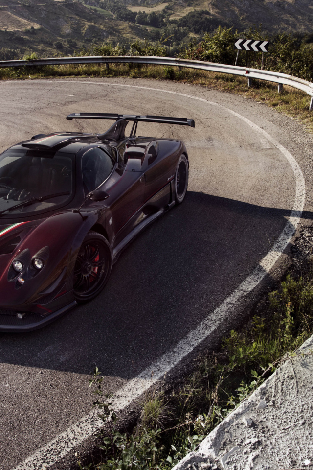 Быстрый бордовый автомобиль Pagani Zonda на крутом повороте