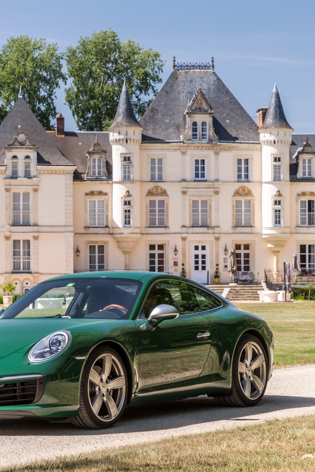 Зеленый спортивный автомобиль Porsche 911 Carrera на фоне дома