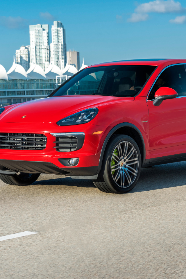 Красный автомобиль Porsche Cayenne на фоне города 