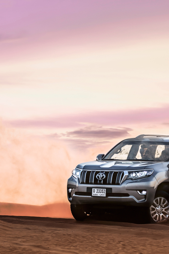 Серебристый внедорожник Toyota Land Cruiser Prado, 2018 едет по песку