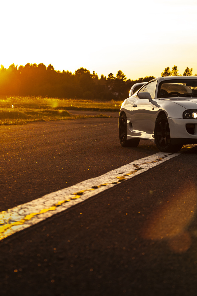 Белый автомобиль Toyota Supra стоит на трассе на рассвете