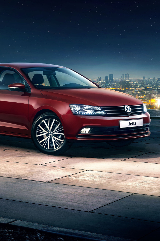 Красный автомобиль Volkswagen Jetta на фоне ночного города