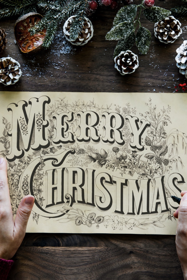 Рисунок с надписью Merry Christmas на столе с новогодними украшениями