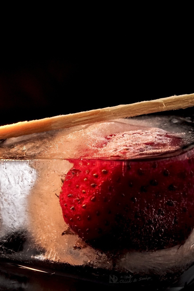 Зажженная спичка на кусочке льда с клубникой 