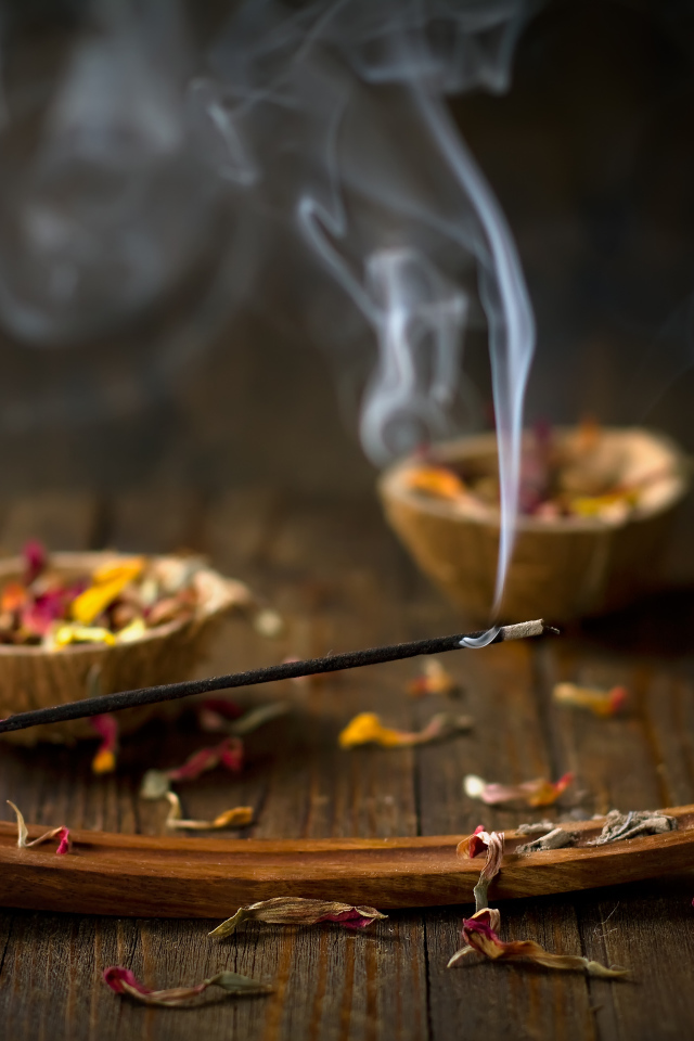 Ароматическая палочка на столе с сухими лепестками цветов