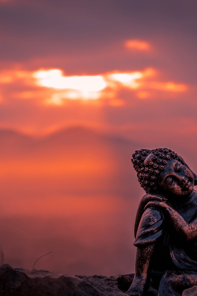 Статуя Будды на фоне солнца на закате