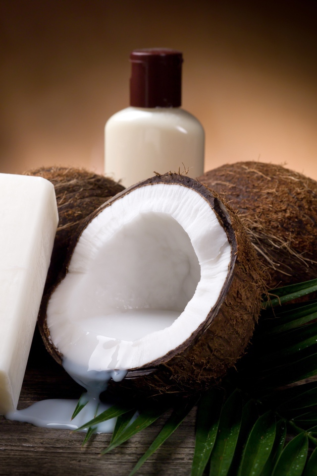 Кокосовое масло с кокосовым мылом и свежими кокосовыми орехами на зеленых листьях