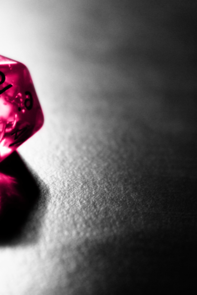 Розовый фигурный кубик отражается серой поверхности стола