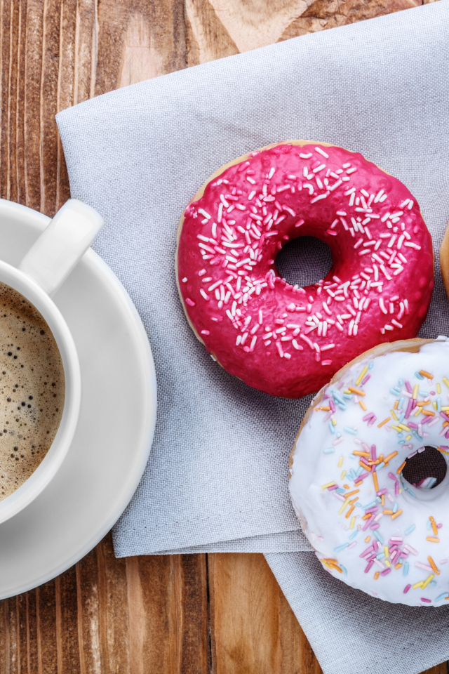 Чашка кофе с тремя аппетитными пончиками на столе