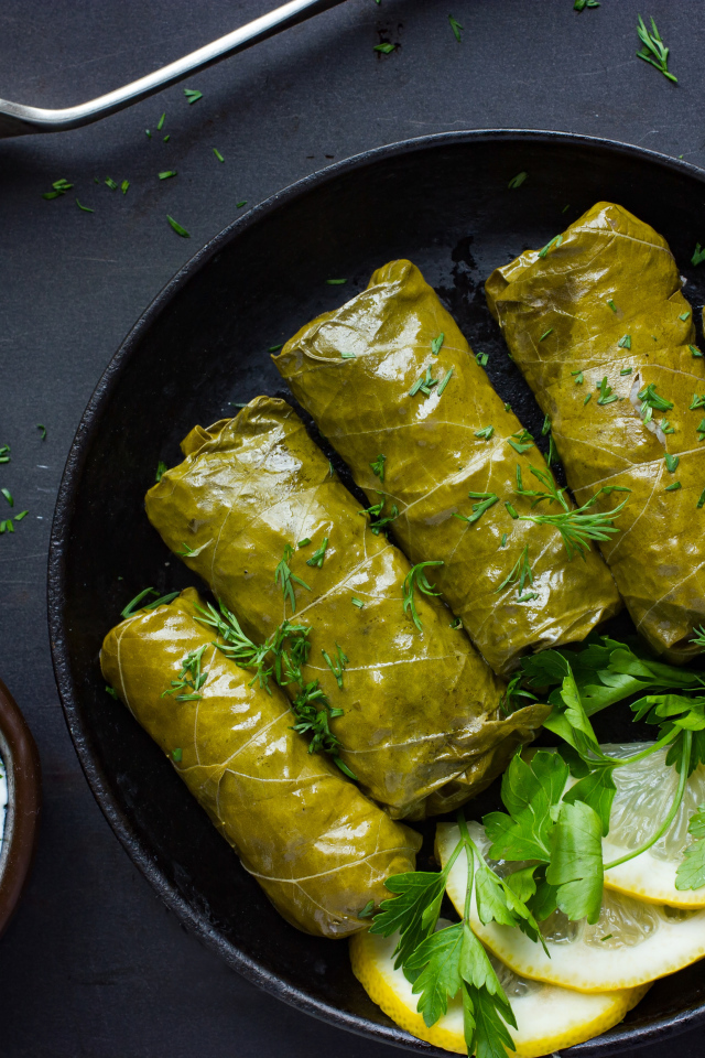 Аппетитная долма с кусочками лимона на столе 