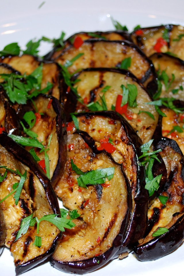 Аппетитные жареные баклажаны на тарелке с зеленью