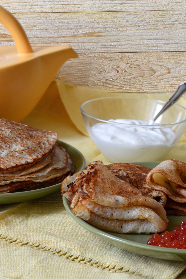 Аппетитные блинчики со сметаной и красной икрой на столе