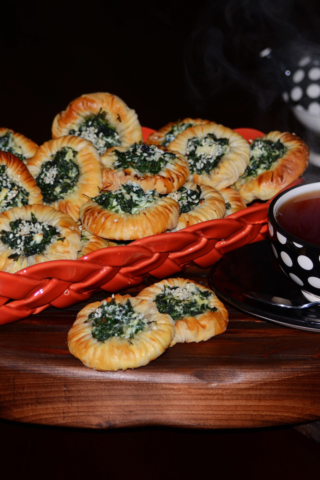 Булочки с зеленью и горячим чаем на черном фоне