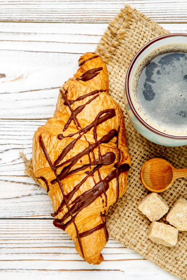 Круассан с шоколадом и чашкой кофе на столе